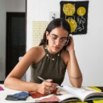 Young woman designer working thoughtfully with fabric swatches at studio.